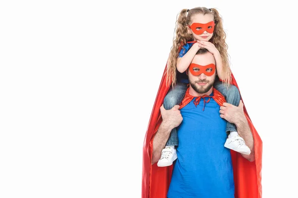 Super-Vater trägt kleine Tochter in Maske und Mantel und schaut isoliert auf weiße Kamera — Stockfoto