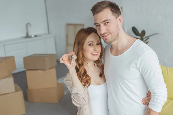 Happy young couple holding key from new apartment and smiling at camera — Stock Photo