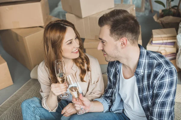 Casal segurando copos de champanhe e sorrindo uns aos outros enquanto celebra a realocação — Fotografia de Stock