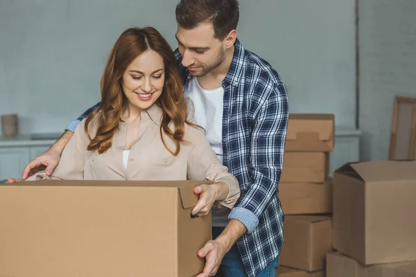 Retrato de pareja sonriente con caja de cartón en casa nueva, concepto de casa móvil - foto de stock