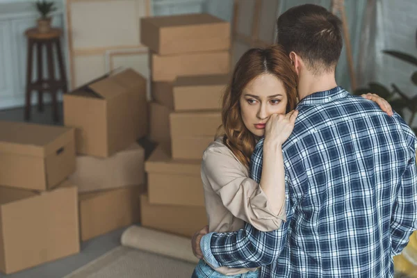 Couple hugging at new apartment full of cardboard boxes, moving home concept — Stock Photo