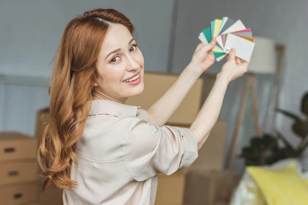 Donna sorridente con pallet di colori per la stanza a nuova casa, concetto di trasferimento — Foto stock