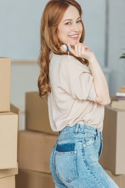Mulher sorridente com chaves de novo apartamento na mão, conceito de realocação — Fotografia de Stock