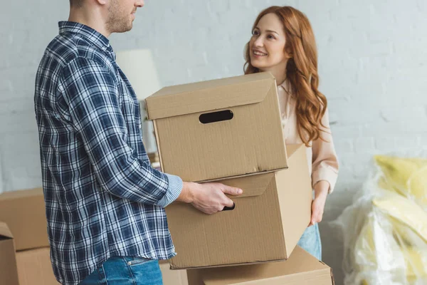 Partial view of smiling woman and husband holding cardboard boxes together at new apartment, moving home concept — Stock Photo