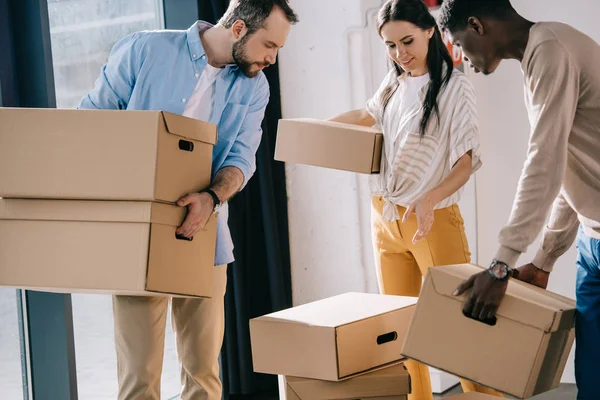 Young multiethnic people carrying cardboard boxes during relocation — Stock Photo