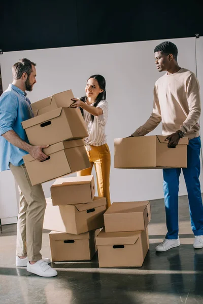 Young multiethnic people holding cardboard boxes during relocation — Stock Photo