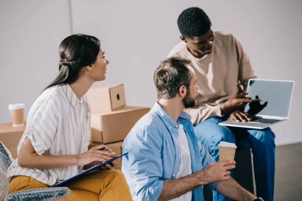 Colegas de trabalho olhando para o empresário afro-americano mostrando laptop com tela em branco no novo escritório — Fotografia de Stock