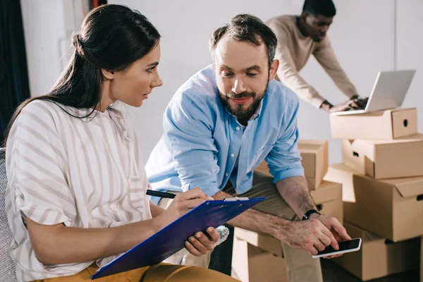 Geschäftskollegen arbeiten während des Umzugs im neuen Büro mit Klemmbrett — Stockfoto