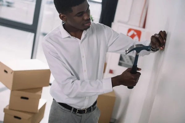 Junger afrikanisch-amerikanischer Geschäftsmann hämmert Nagel in neues Büro — Stockfoto