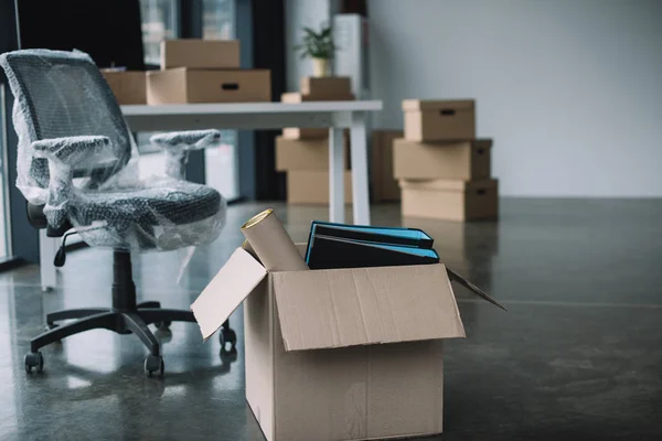 Cardboard box with folders and office supplies in floor during relocation — Stock Photo