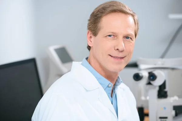 Sourire beau médecin regardant la caméra dans la clinique — Photo de stock