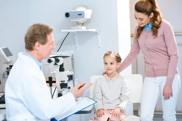 Mother and daughter listening ophthalmologist in consulting room — Stock Photo