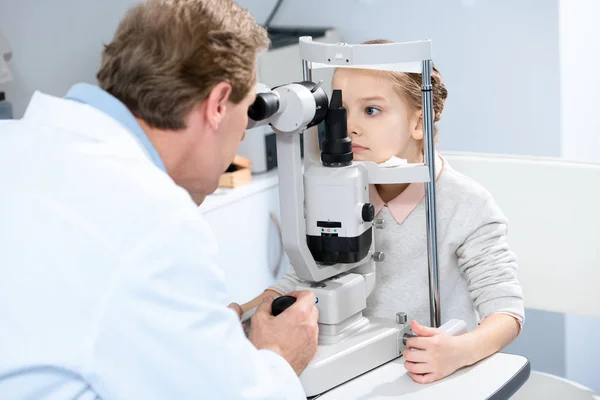 Окулист изучает зрение ребенка-подростка с щелевой лампой в клинике — стоковое фото