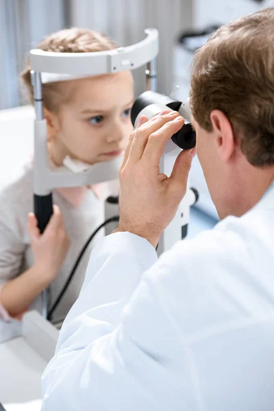 Image recadrée de l'ophtalmologiste examinant la vision de l'enfant préadolescent avec lampe à fente en clinique — Photo de stock