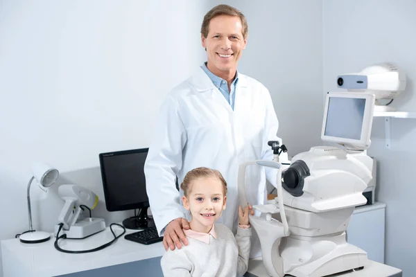 Oftalmologo sorridente e bambino pre-adolescente che guarda la fotocamera in clinica — Foto stock