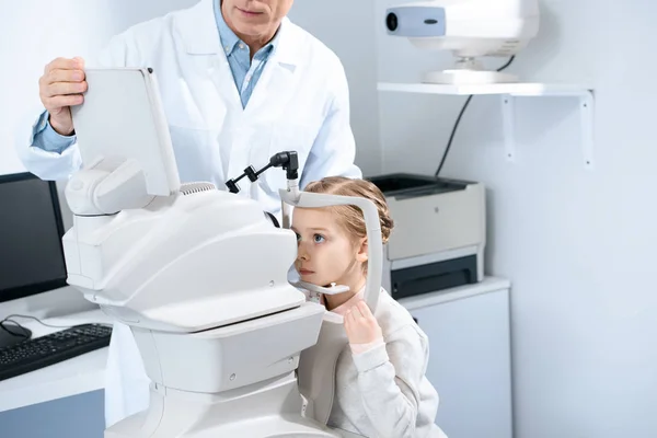 Imagen recortada del oftalmólogo que examina la visión del niño preadolescente en la clínica - foto de stock