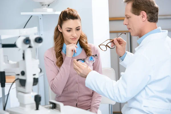 Augenarzt gibt Patientengläser mit unterschiedlichen Linsen in Klinik — Stockfoto