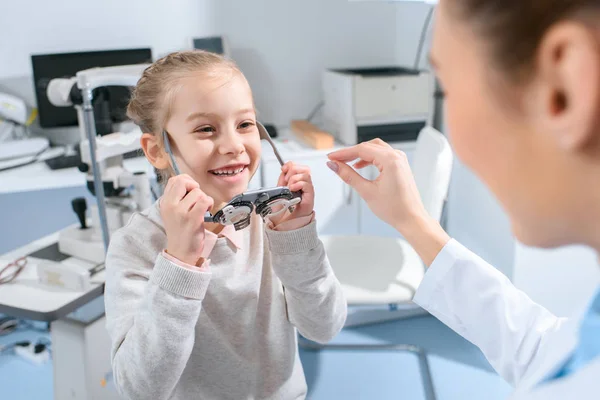 Optometrist examining child eyes with trial frame in clinic — Stock Photo