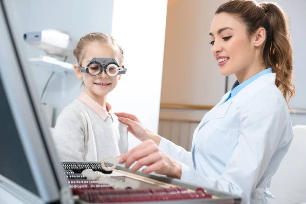 Oftalmólogo examinando los ojos del niño con marco de ensayo y lentes - foto de stock