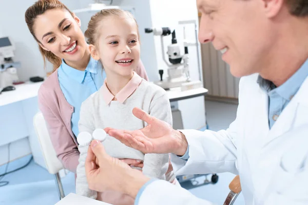 Mãe feliz e filha visitando oftalmologista e escolhendo lentes oculares na clínica — Fotografia de Stock