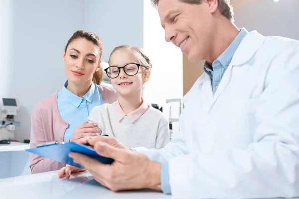 Mother and daughter in glasses visiting oculist in clinic — Stock Photo