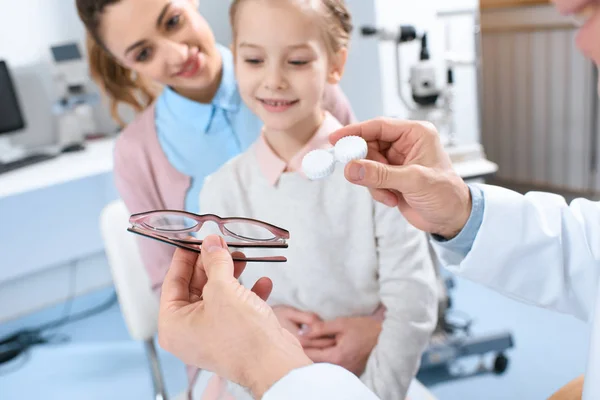 Mother and daughter visiting ophthalmologist and choosing eyeglasses or eye lenses in clinic — Stock Photo