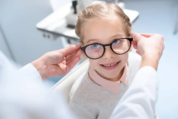 Oculista y niño pequeño en gafas en clínica óptica - foto de stock