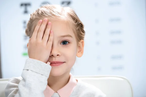 Маленький ребенок закрывает глаза с тестом на глаза позади — стоковое фото