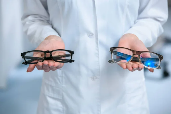 Vista ritagliata dell'optometrista che tiene diversi occhiali in mano — Foto stock