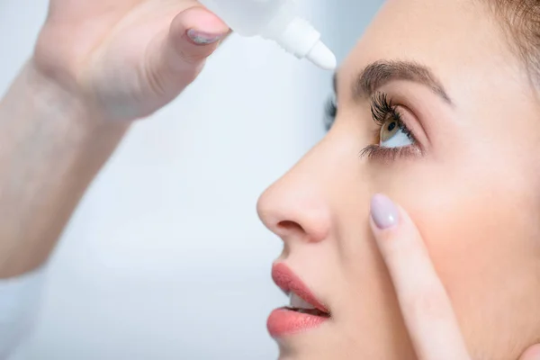 Perfil de hermosa mujer goteando gotas para los ojos - foto de stock