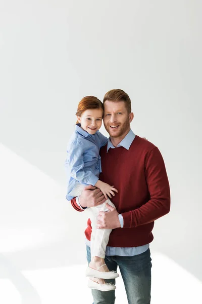 Happy father carrying adorable little daughter and smiling at camera on grey — Stock Photo