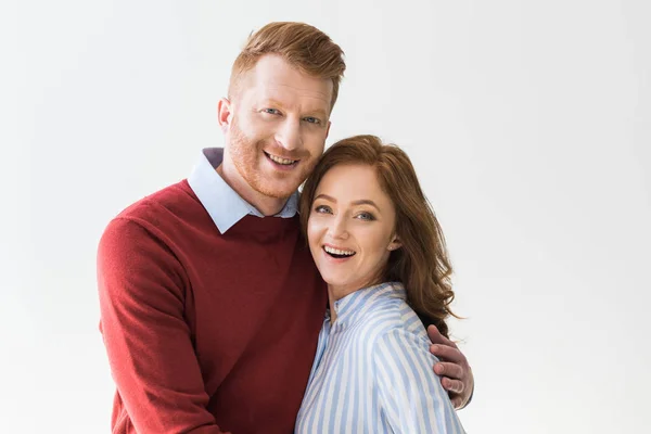 Retrato de alegre pareja pelirroja de pie juntos y sonriendo a la cámara aislada en gris - foto de stock