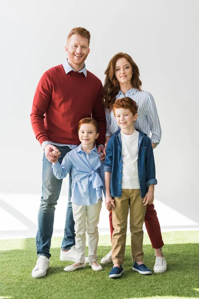 Heureux rousse famille debout ensemble et souriant à la caméra sur gris — Photo de stock