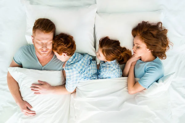 Семья с двумя детьми, спящими вместе в постели — стоковое фото