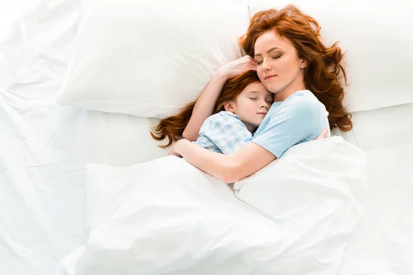 Красива мати і дочка обіймаються і сплять разом у ліжку — стокове фото