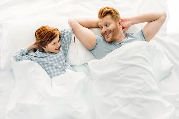 Щасливий батько і дочка лежать разом у ліжку і посміхаються один одному — стокове фото