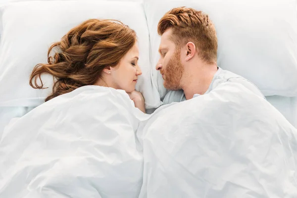 Vue de dessus du beau couple rousse dormant face à face au lit — Photo de stock