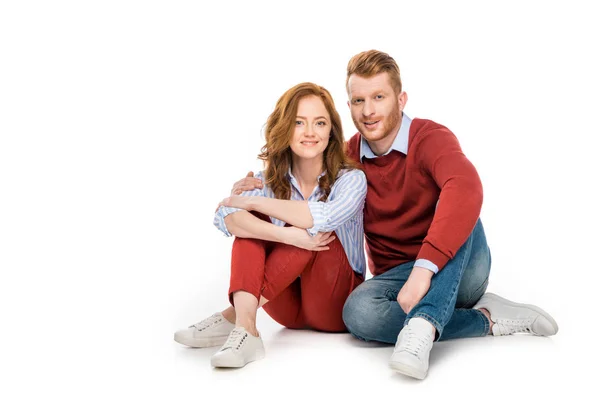 Belo casal ruiva feliz sentado juntos e sorrindo para a câmera isolada no branco — Fotografia de Stock