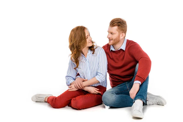 Beautiful happy redhead couple sitting together and smiling each other isolated on white — Stock Photo