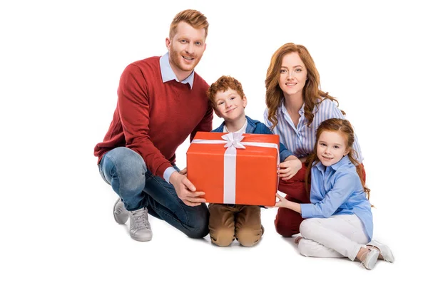 Glücklich rothaarige Familie hält große Geschenkbox und lächelt in die Kamera isoliert auf weiß — Stockfoto