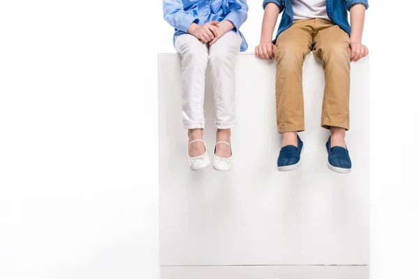 Cropped shot of children sitting on white cube isolated on white — Stock Photo