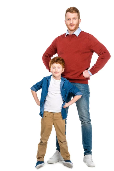 Pelirroja padre e hijo de pie con las manos en la cintura y mirando a la cámara aislada en blanco - foto de stock