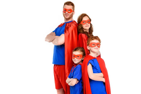 Familie in Superheldenkostümen steht mit verschränkten Armen und blickt vereinzelt in die Kamera — Stockfoto