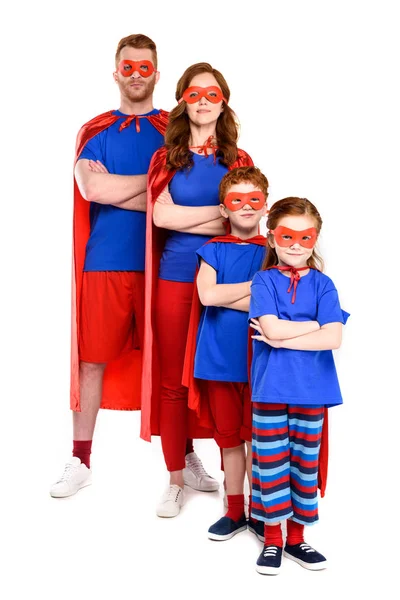 Confident super family in costumes standing with crossed arms and looking at camera isolated on white — Stock Photo