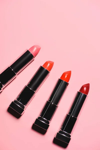 Top view of various lipsticks in row on pink surface — Stock Photo
