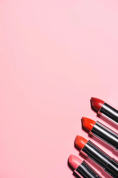 Vista superior de los diferentes lápices labiales en fila en la superficie rosa - foto de stock