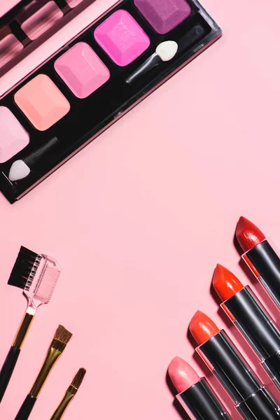 Vista superior de varios suministros de maquillaje en la superficie rosa - foto de stock