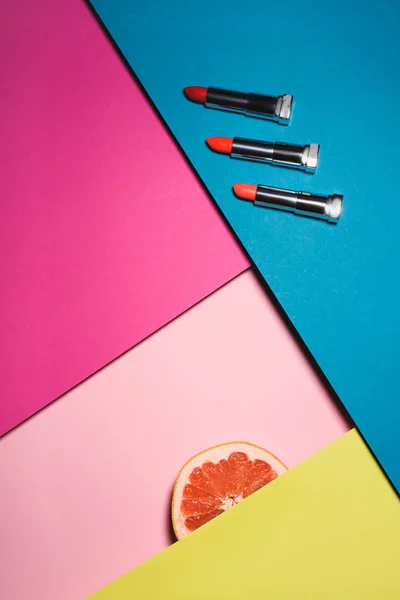 Vista superior de varios lápices labiales con sllice naranja en superficies coloridas - foto de stock