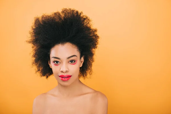 Улыбающаяся африканская американка с креативным красным макияжем, изолированным на желтом — стоковое фото