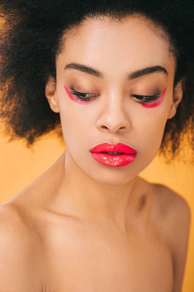 Young african american woman with creative red makeup isolated on yellow — Stock Photo